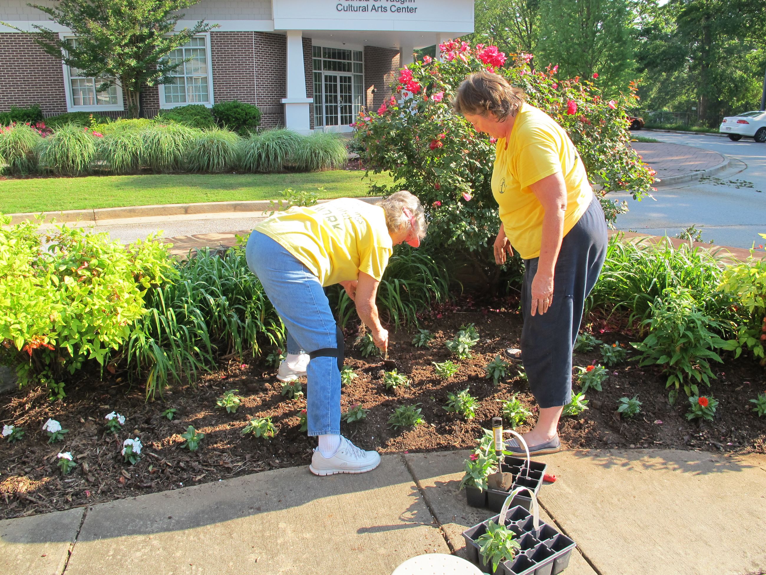 Two volunteers planting flowers at the Ford Center.