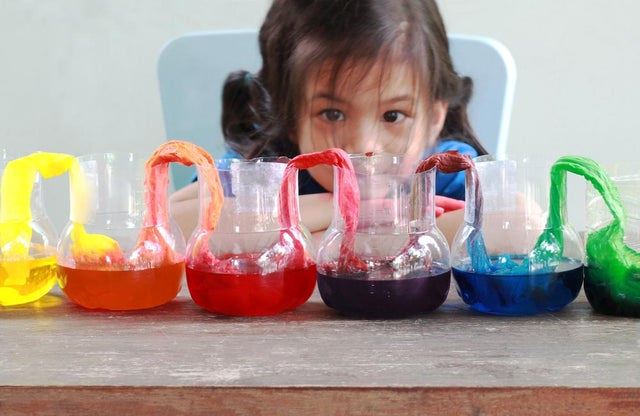 Asian girl watching a rainbow experiment. Paper towels draped in colored water to turn rainbow color