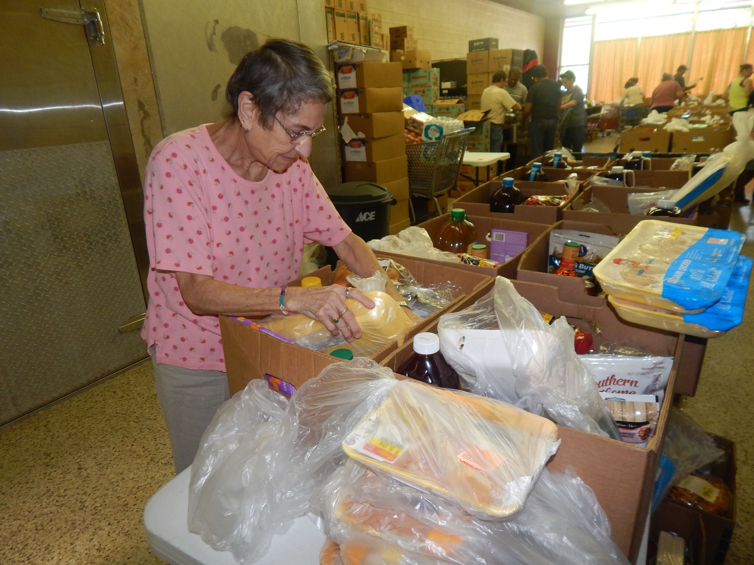 Older lady placing milk jugs in boxes for food pantry distribution.